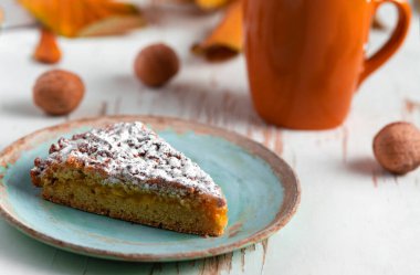 Kurumuş yapraklar ve sonbahar kompozisyonu ile sıcak çayla servis edilen fırında turta.