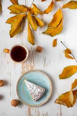 Kurumuş yapraklı ve cevizli sıcak çayla servis edilen fırında turta, sonbahar kompozisyonu.
