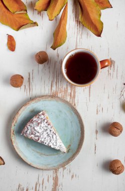 Kurumuş yapraklı ve cevizli sıcak çayla servis edilen fırında turta, sonbahar kompozisyonu.