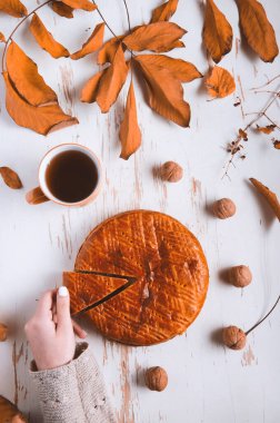 Sonbahar yapraklı ve cevizli, sonbahar kompozisyonu olan bir fincan çayla eski püskü bir masada servis edilen ev yapımı turta.