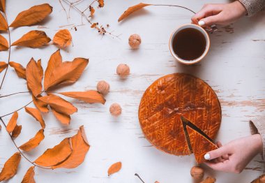 Sonbahar yapraklı ve cevizli, sonbahar kompozisyonu olan bir fincan çayla eski püskü bir masada servis edilen ev yapımı turta.