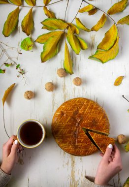 Sonbahar yapraklı ve cevizli, sonbahar kompozisyonu olan bir fincan çayla eski püskü bir masada servis edilen ev yapımı turta.