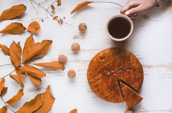 Sonbahar yapraklı ve cevizli, sonbahar kompozisyonu olan bir fincan çayla eski püskü bir masada servis edilen ev yapımı turta.