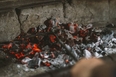Şöminede kömür yakıyor, kömürlere yakın çekim yapıyor.