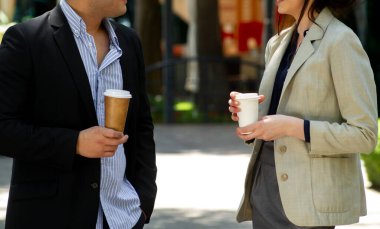 Kâğıt kahve bardakları tutan iş adamları. İş adamı ve iş kadını dışarıda kahve içiyor..
