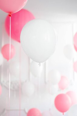 Beyaz balonun dikey görüntüsü, odanın her yerinde pembe ve beyaz balonlar.