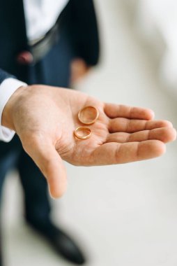 İki alyans bir adamın avucunda, üst tarafta.