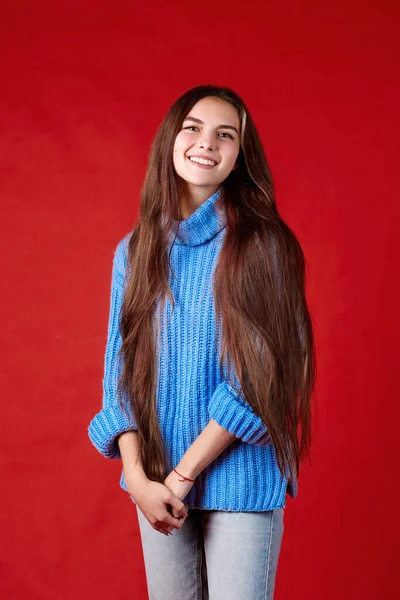 Красивая девушка в теплом свитере на красном фоне Стоковое Изображение