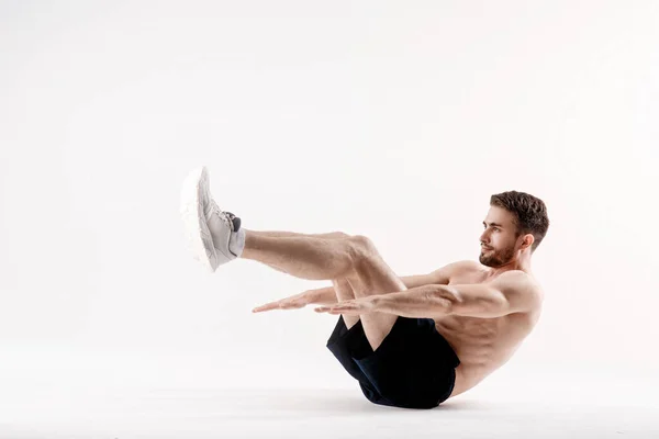 Ung man med skägg av en sport fysik gör en övning på musklerna i bukhålan på en vit isolerad — Stockfoto