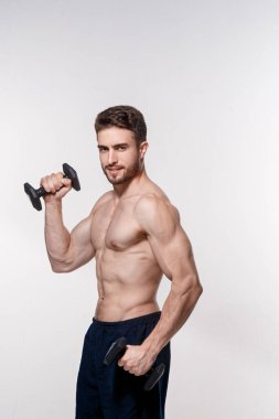 Beyaz arka plandaki genç sporcu dambılları kaldırıyor. Sakallı bir adamı eğitmek.