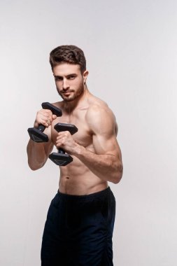 Beyaz arka plandaki genç sporcu dambılları kaldırıyor. Sakallı bir adamı eğitmek.