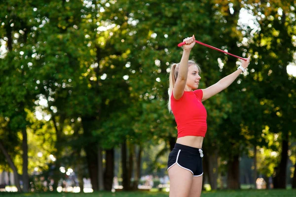 Mujer joven está entrenando con bandas de goma al aire libre. Concepto de estilo de vida activo saludable. chica haciendo ejercicio en el parque en —  Fotos de Stock