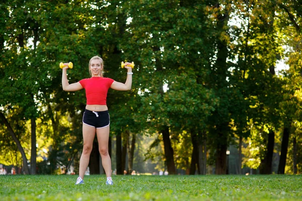 Una joven entra para practicar deportes al aire libre. chica con pelo rubio está entrenando en el parque en la naturaleza. —  Fotos de Stock