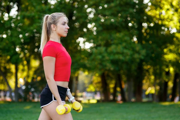 Una joven entra para practicar deportes al aire libre. chica con pelo rubio está entrenando en el parque en la naturaleza. —  Fotos de Stock