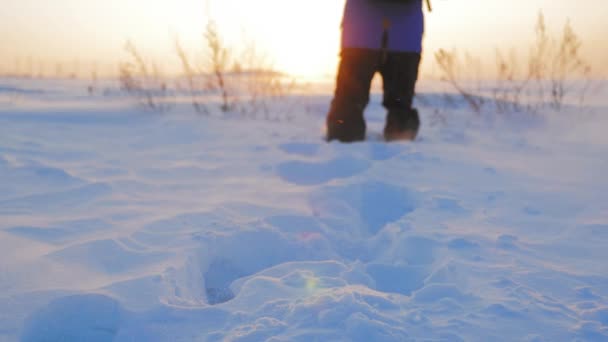 Silueta muže s batohem kráčejícího po zimní krajině při západu slunce. Koncept dobrodružství činnost koníček extrémní. Sněhem se prochází horolezec. zimní turistika.