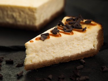 Yakın plan ev yapımı klasik cheesecake New York 'un üzerine karamel sosu ve çikolata parçacıkları döküldü.