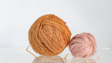 Aydınlık bir arkaplana yerleştirilmiş iki farklı boyutta örgü ipliği. Tarafsız sıcak renkler örgü, tığ işi ve el işi ile ilişkili basit, sade bir hayat yaratır. Tekstil malzemeleri ve yaratıcı ev aktiviteleri kavramı.