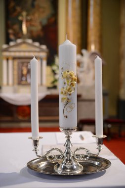 Katolik kilisesinin sunağında gümüş bir şamdanda üç tören mumu.