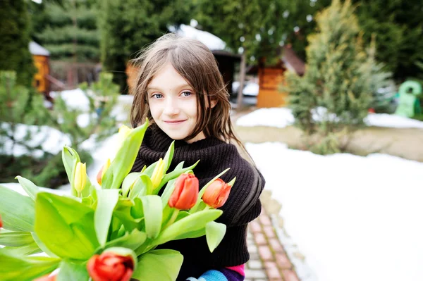 Bruneta dítě dívka s tulipány mimo — Stock fotografie