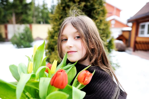 Brunette jongen meisje met tulpen buiten — Stockfoto