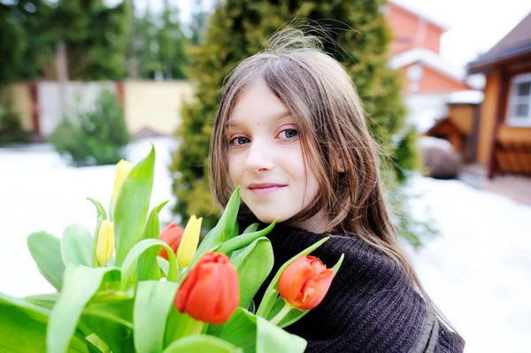 Brunett kid flicka med tulpaner utanför — Stockfoto