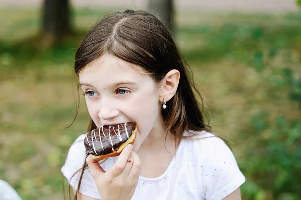 Милая девочка ест сладкие пончики — стоковое фото