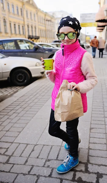 Fun kid girl in hat drinking on city street — Stock Photo, Image