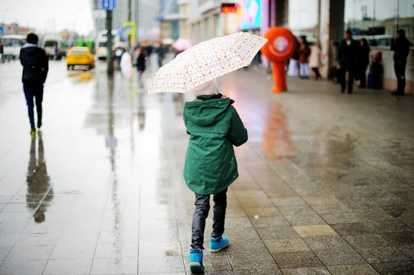 Mädchen mit Regenschirm läuft in Stadtstraße Stockfoto