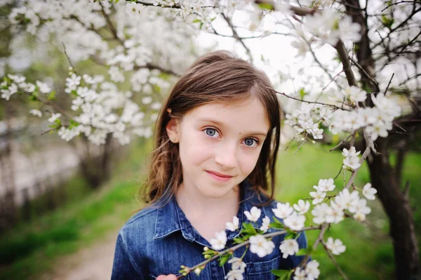 Kid girl in blooming garden — Stock Photo, Image