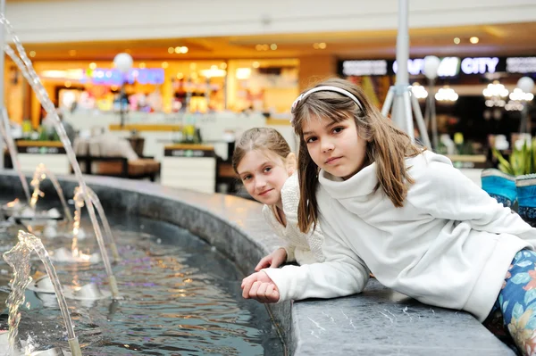 Twee schattige kleine meisjes spelen met een fontein stad — Stockfoto