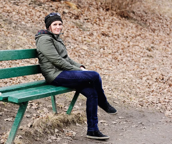 Jovem bela mulher sentada no banco no parque . — Fotografia de Stock