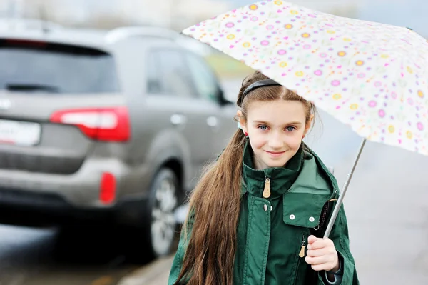 Mädchen mit Regenschirm läuft in Stadtstraße Stockbild