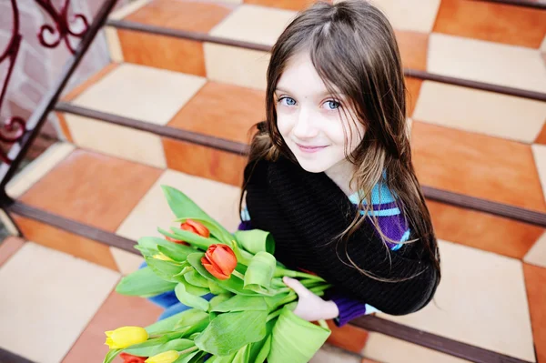 Brunette jongen meisje met tulpen buiten — Stockfoto