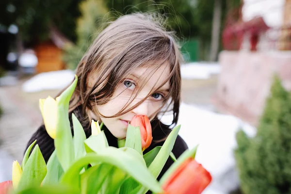 Bruneta dítě dívka s tulipány mimo — Stock fotografie