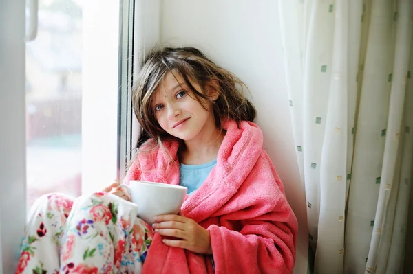 Beautiful little girl in bathrobe with cup of tea — Stock Photo, Image