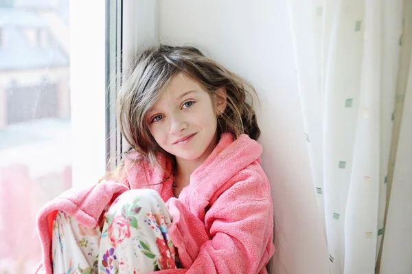 Bornoz pencere yakınındaki güzel küçük kız — Stok fotoğraf