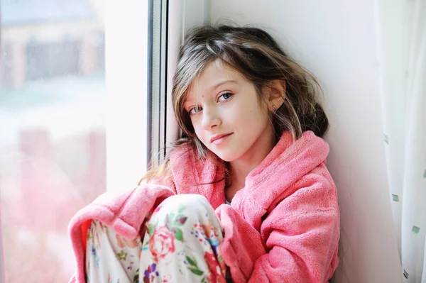 Beautiful little girl in bathrobe near window — Stock Photo, Image