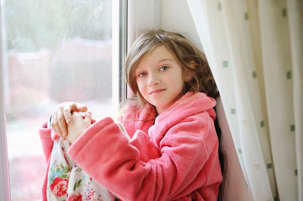 Beautiful little girl in bathrobe near window — Stock Photo, Image