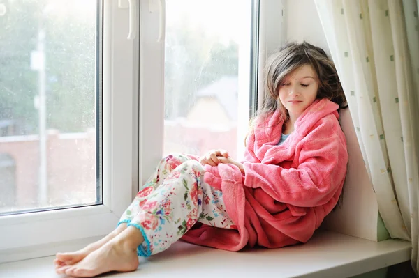 Krásná holčička v županu u okna — Stock fotografie