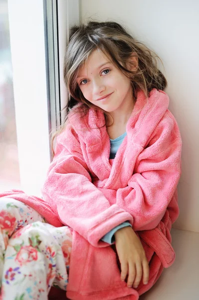 Beautiful little girl in bathrobe near window — Stock Photo, Image