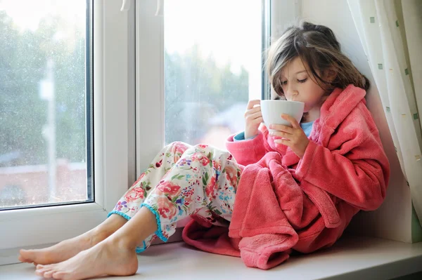 Vacker liten flicka i morgonrock med kopp te — Stockfoto