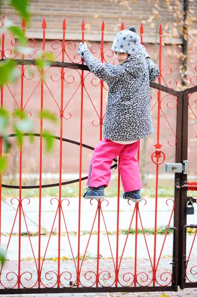 Kid girl climbed on a fence — Stock Photo, Image