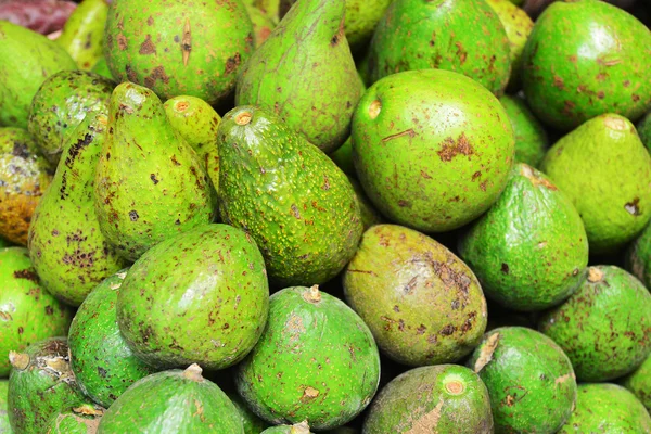 Avocado achtergrond. Verse groene avocado op een markt-stail — Stockfoto