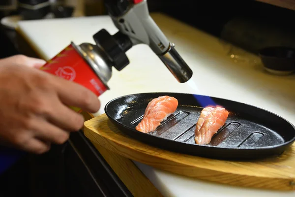 Chef-kok met behulp van een fakkel branden op zalmsushi — Stockfoto