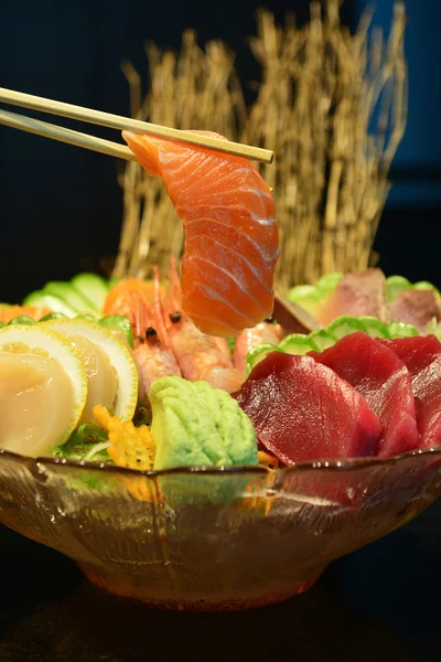 Plátky syrového lososa s hůlkami, které ji drží na sashimi set — Stock fotografie