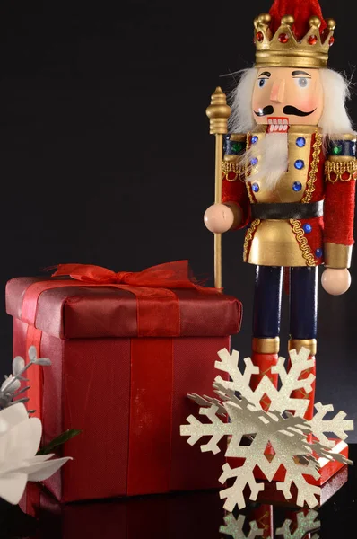 Ένα Χριστουγεννιάτικο Καρυοθραύστης Στέκεται Δίπλα Ένα Κόκκινο Δώρο Για Την — Φωτογραφία Αρχείου