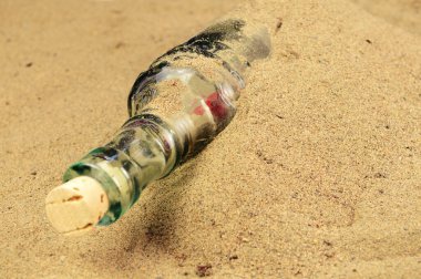 Plajda kaybolmuş bir cam şişe kısmen kumla kaplı..