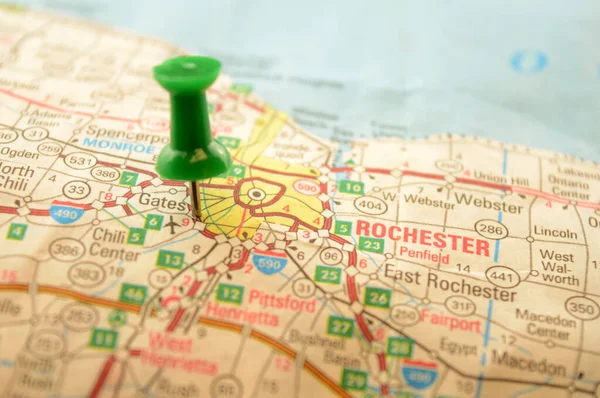 A green pin pressed into a map detailing the point of interest referring to the place named Rochester, New York, of the United States of America.