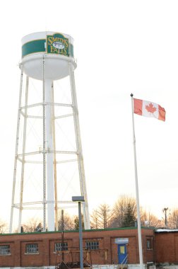 SMITHS FALls, ONTARIO, CANADA, 10 Mart 2021: Smiths Falls Watertower ve Kanada Bayrağı 'nın küçük kasabadaki Beckwith St Bridge bölgesinden bir görüntüsü.
