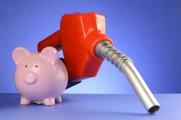A concept of saving money at the gas pumps using a piggy bank and red fuel pump over a blue background.